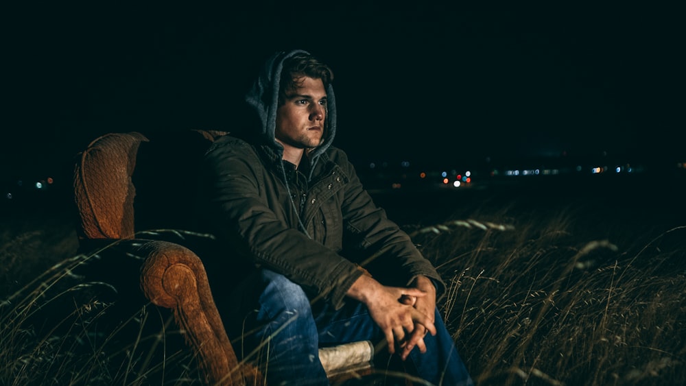 man in brown full-zip jacket sitting on brown suede armchair