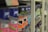 A close-up view of shelves filled with various cans of paint, with a focus on colorful labels, including pink, orange, and blue hues. The depth of field blurs the background, highlighting the foreground cans.