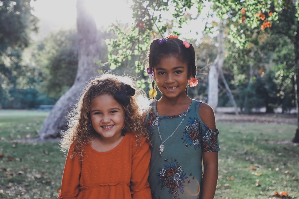 two dressed children standing against trees