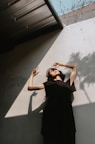 a woman in a black dress leaning against a wall