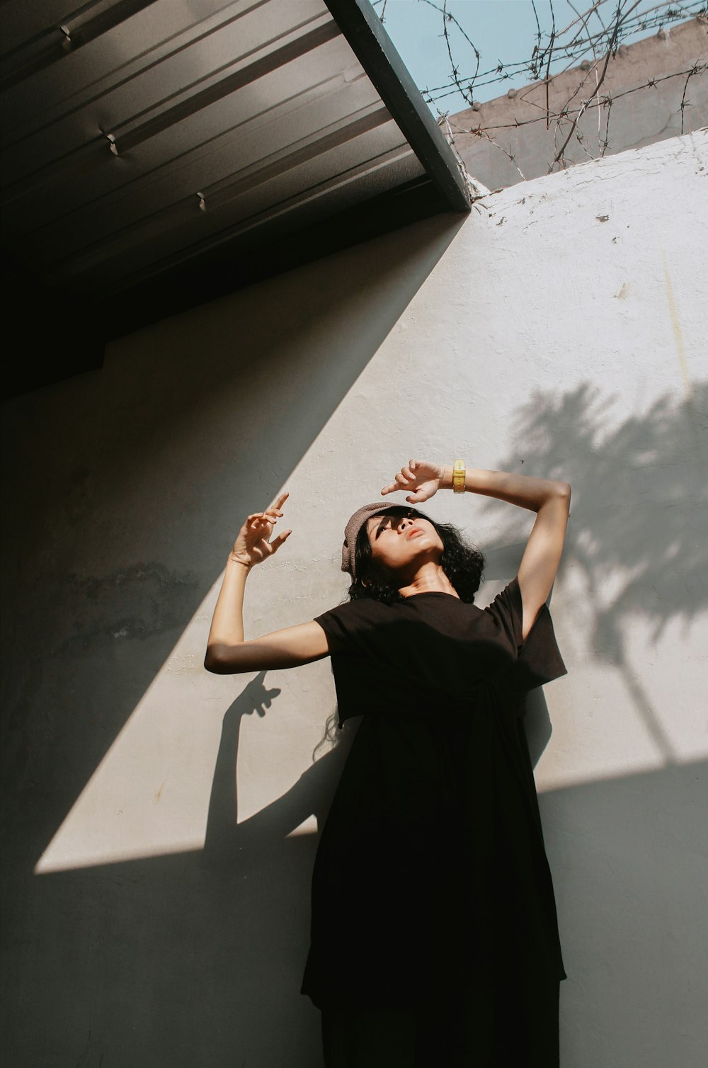 a woman in a black dress leaning against a wall