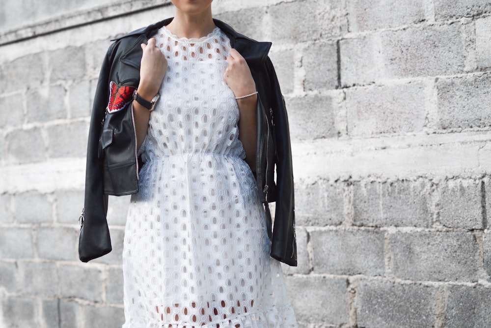 woman with coat beside cinder block wall