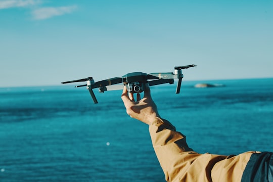 person holding grey drone in front of sea in Atlantic Ocean Road Norway