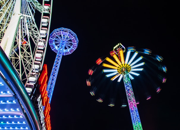 Fairground rides spinning with avatars laughing and neon lights streaking through the night sky.