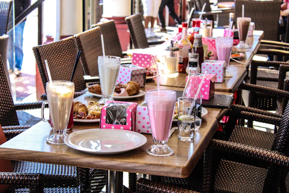 A beautifully plated arrangement of vibrant shakes, coffees, and teas on a glossy black tray with golden accents.
