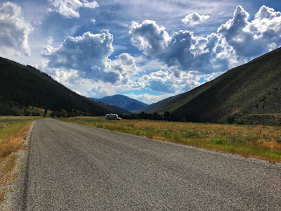 A scenic road with a rental car parked beside a beautiful mountain view.