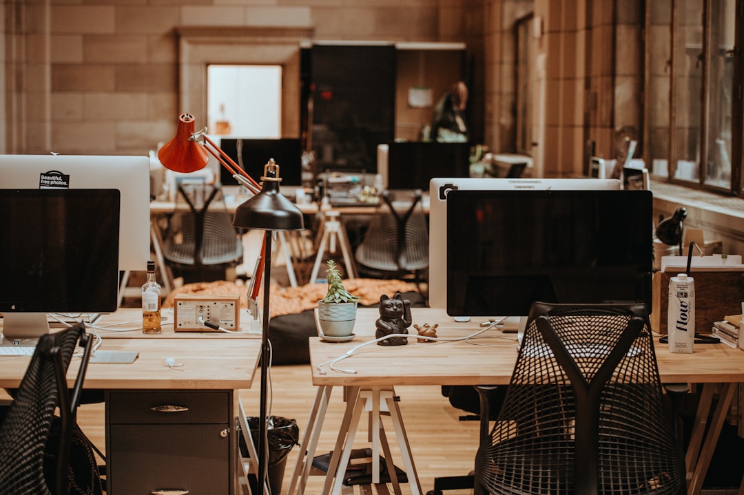 turned off flat screen monitors on top of beige desks, Desktop setup at Unsplash HQ