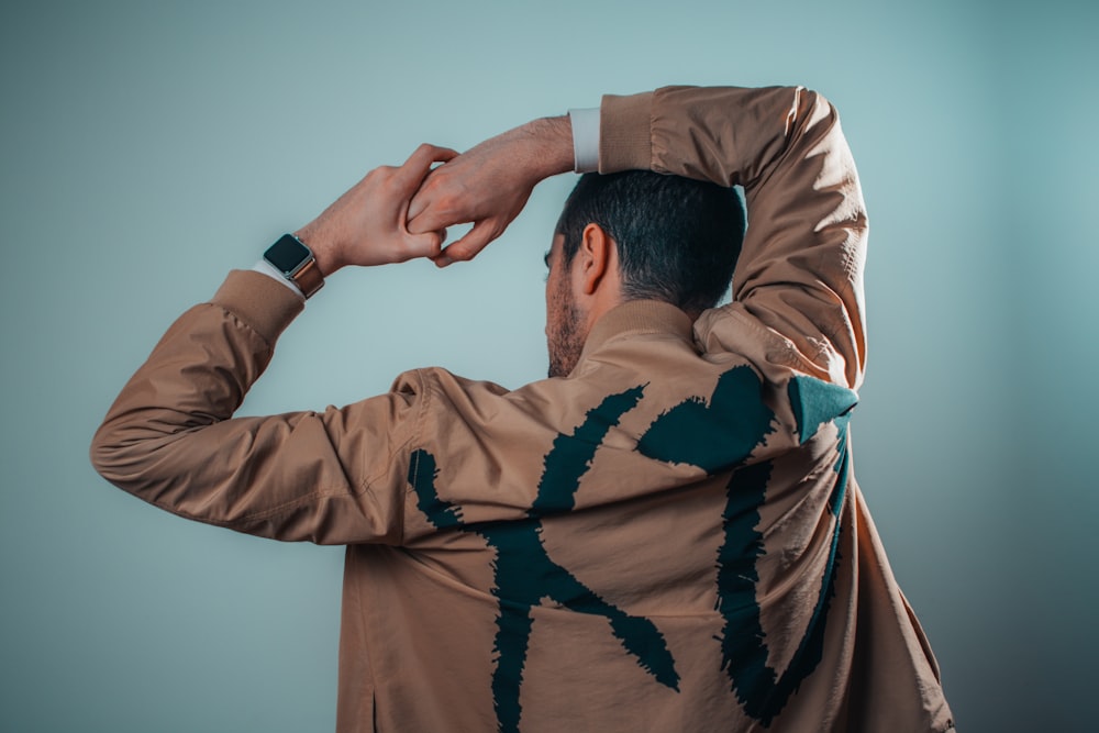 man wearing brown jacket facing green wall