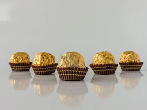 Close-up of a chocolatier delicately handcrafting a dark chocolate truffle with gold leaf accents.