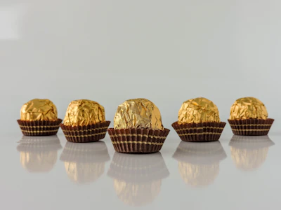 Close-up of a chocolatier delicately handcrafting a dark chocolate truffle with gold leaf accents.