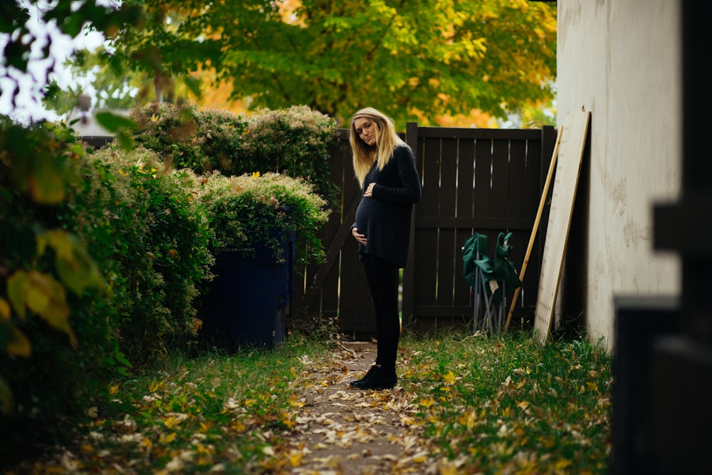 woman standing near brown wooden fence