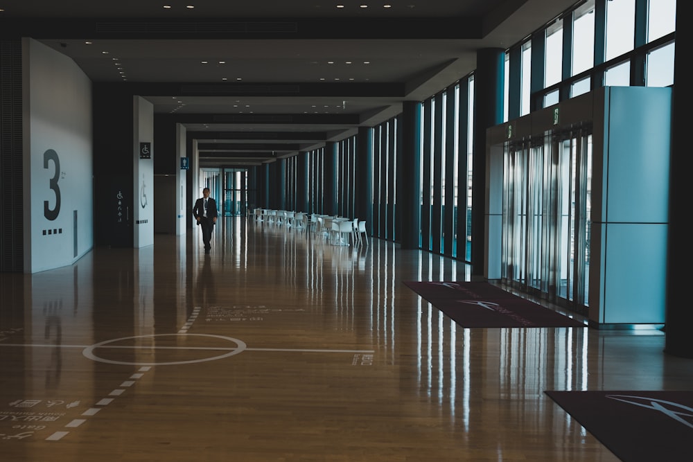 man in black formal suit jacket walking on hallway during daytime