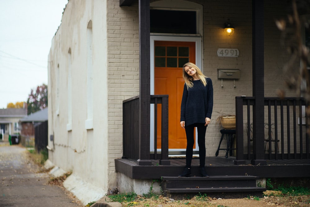 a woman standing on a porch in front of a house