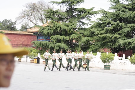 A group of soldiers in uniform training in a lush green field.