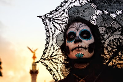 person with skull face paint and umbrella dia de los muertos teams background
