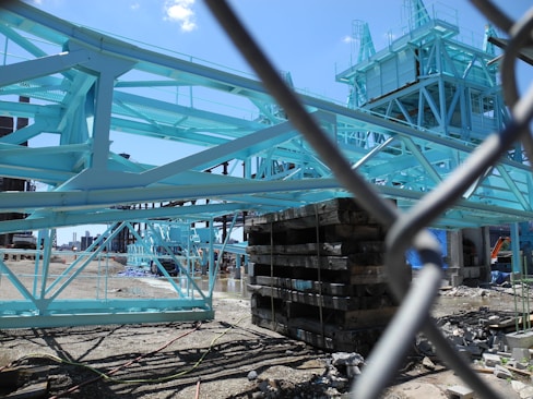 A team of engineers reviewing structural blueprints on a construction site with steel frameworks in the background.