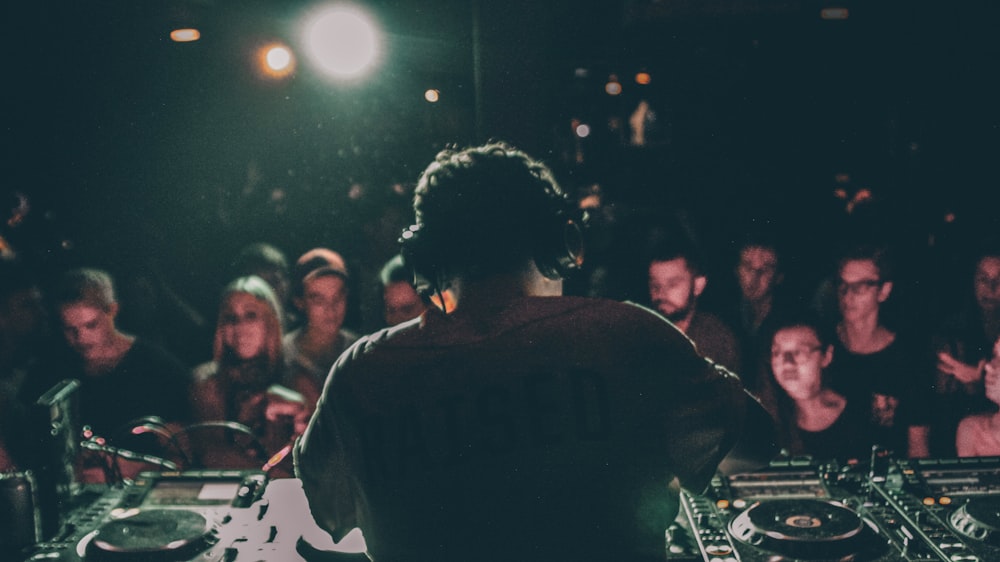 Mann im grauen Hemd bedient schwarzen DJ-Plattenspieler im Raum