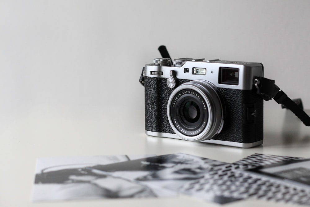 Fotocamera a pellicola nera e grigia vicino a foto stampate