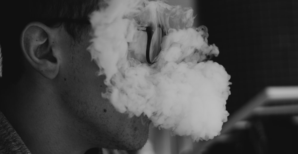 Photo en niveaux de gris d’un homme qui fume