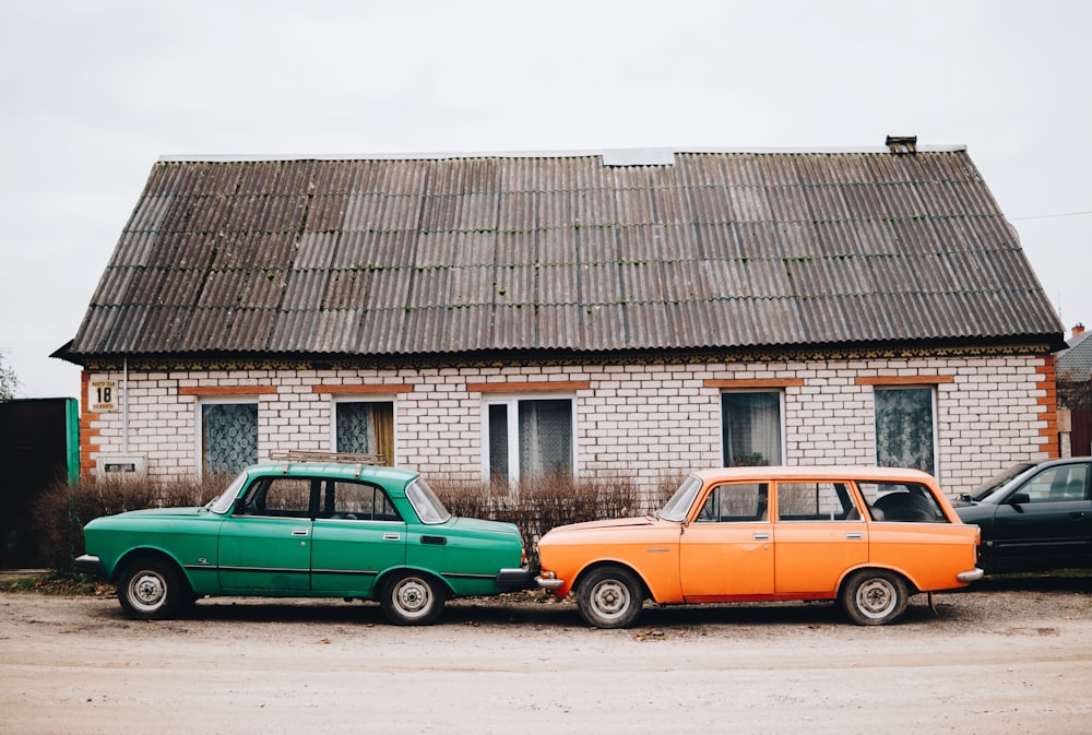 green sedan and orange station wagon beside building