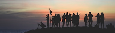 silhouette photography of people gathered together on cliff