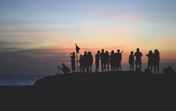 silhouette photography of people gathered together on cliff