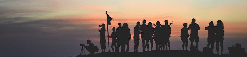 silhouette photography of people gathered together on cliff