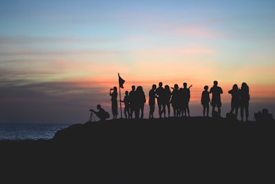 silhouette photography of people gathered together on cliff team teams background