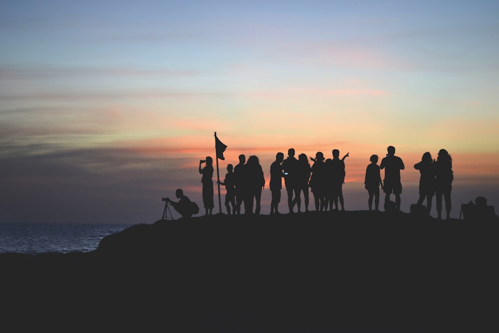 silhouette photography of people gathered together on cliff