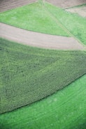 Aerial view of farmland with patches of green and brown showing diverse soil treatments