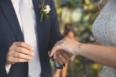 A couple exchanging rings during an outdoor wedding ceremony.