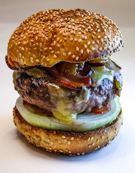 Close-up of a sizzling grilled burger with melted cheese and fresh toppings.