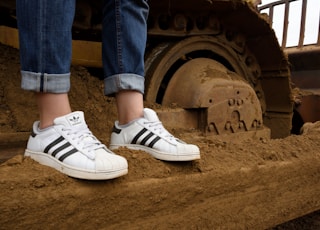 person wearing blue denim jeans and white adidas sneakers