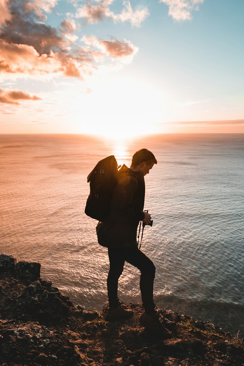 man standing near the shore during sunset