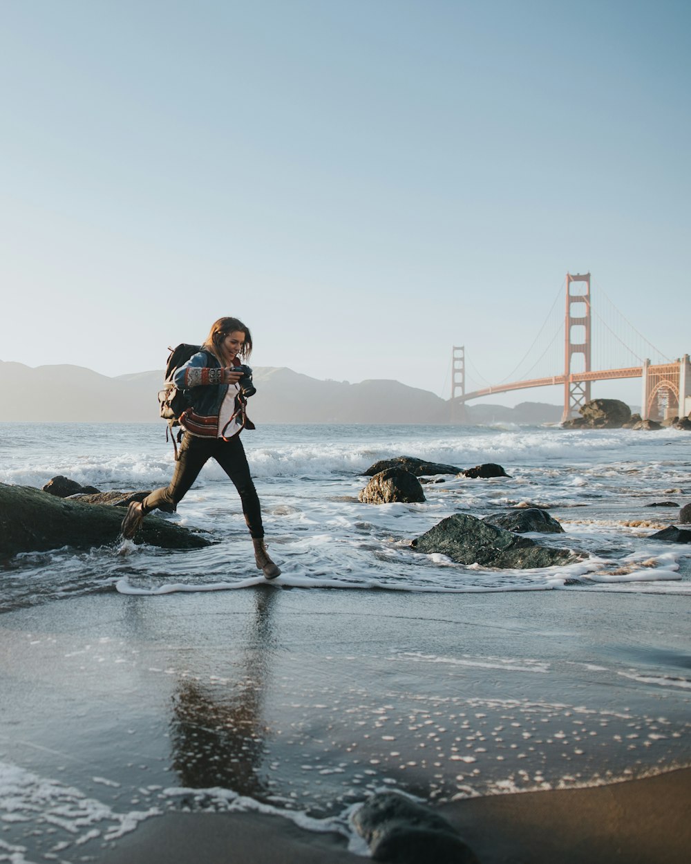 woman jumping over body of water