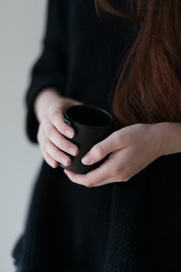 woman in black long sleeve shirt holding black ceramic mug