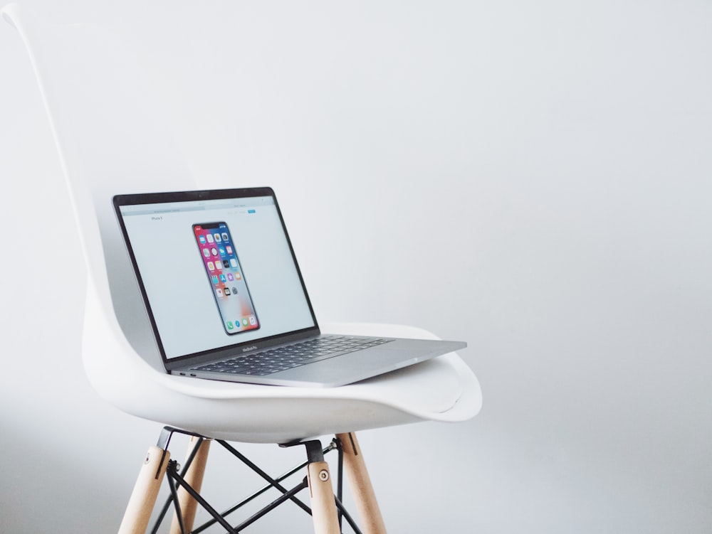 turned on MacBook on top of white chair