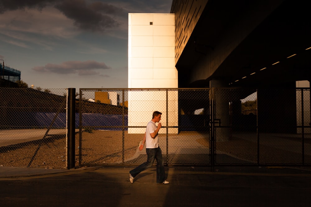 man walking in front of chain link fence