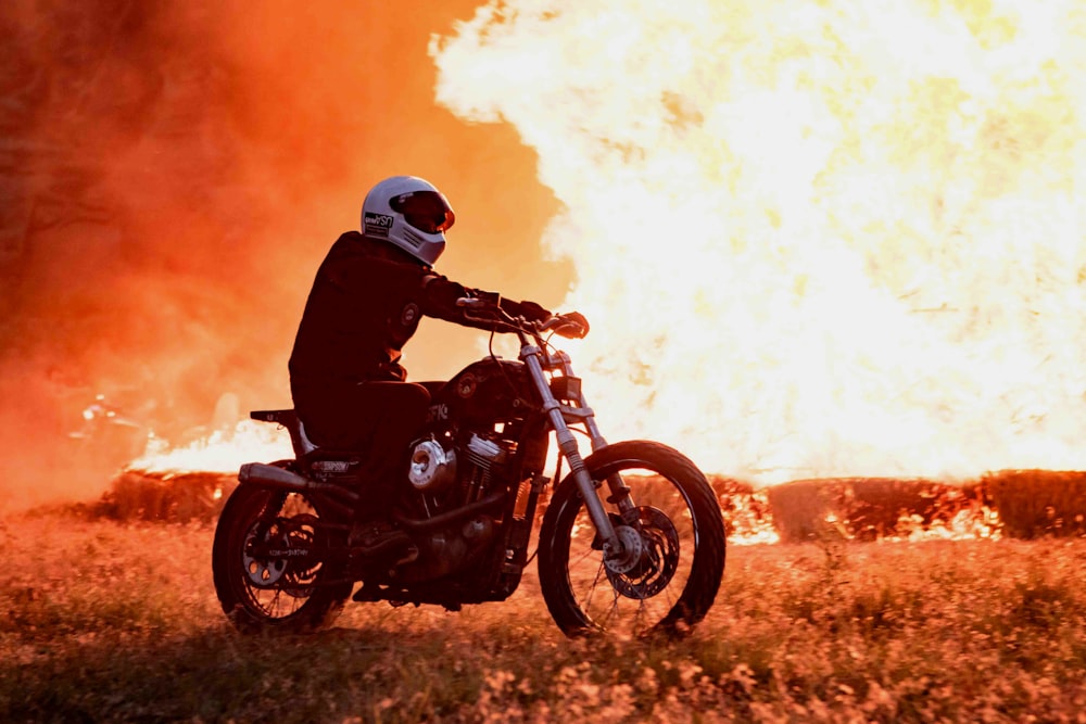 불타는 구조물 근처에서 오토바이를 타고 있는 사람