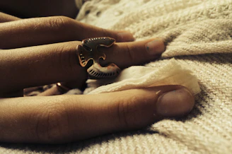 Close-up of a delicate silver and gold ring resting on a textured dark fabric, highlighting craftsmanship.