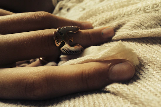 Close-up of a delicate silver and gold ring resting on a textured dark fabric, highlighting craftsmanship.