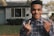 A happy homeowner shaking hands with a real estate agent outside a suburban house.