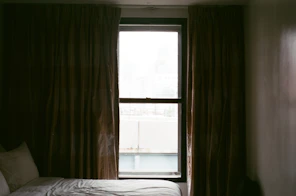 A serene bedroom scene featuring blackout curtains drawn shut, creating a calm, dark environment.
