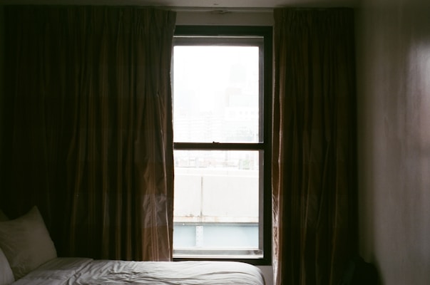 A cozy bedroom window dressed with dark gray blackout curtains softly filtering morning light.
