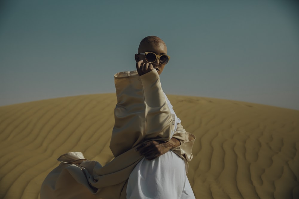 homme en vêtements bruns et blancs sur le désert pendant la journée