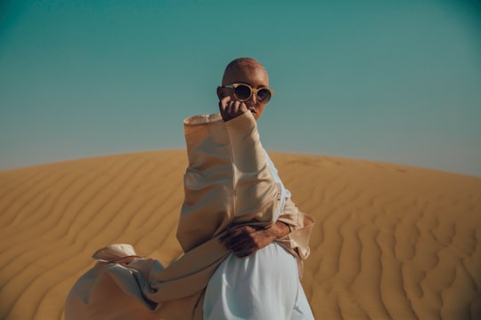 man in brown and white apparel on desert during daytime in Abu Dhabi United Arab Emirates