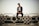 man sitting on white metal fence during daytime