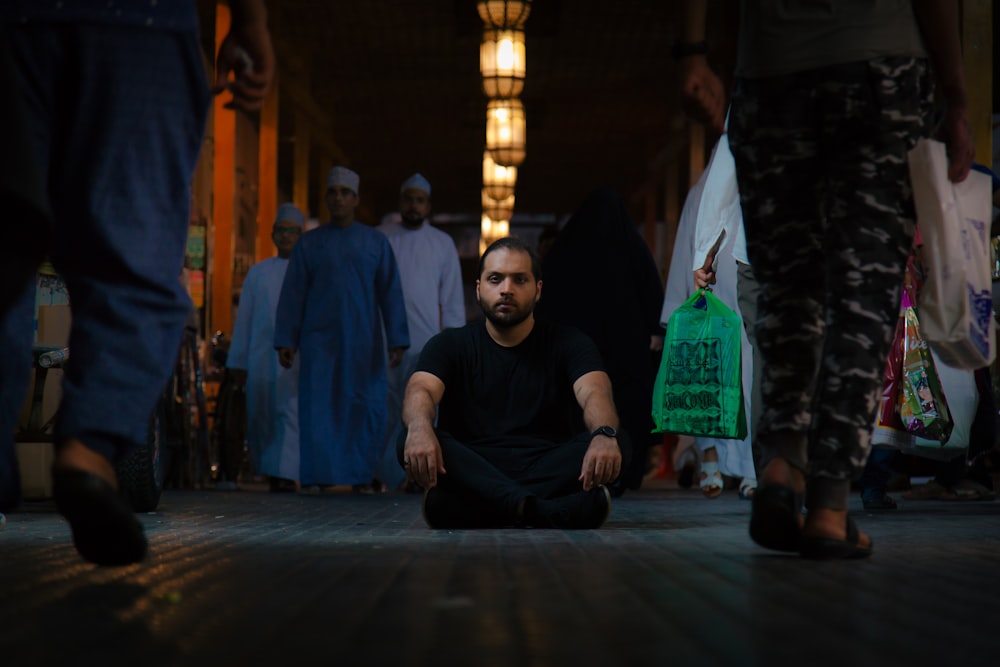 man in black shirt sitting on floor surrounded by people