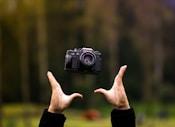 photographie en focus sélectif d’une personne lançant un appareil photo bridge noir