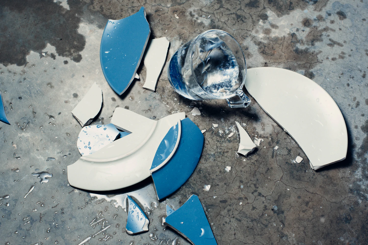 Blue and white ceramic shards scattered on a concrete floor